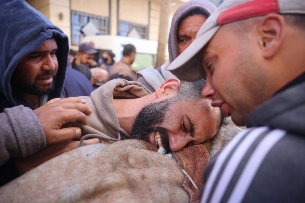 A Palestinian man mourns relatives, killed in an Israeli airstrike, ahead of their funeral in the Nuseirat refugee in the central Gaza Strip on Friday. AFP