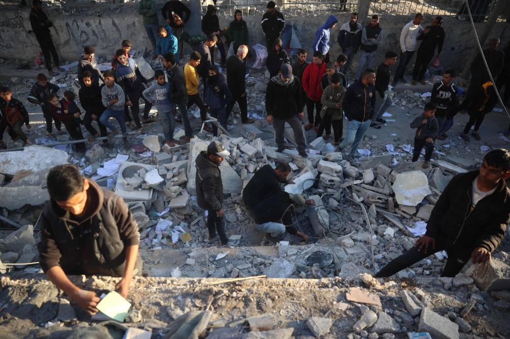 Palestinians stand next to the rubble of a building after an Israeli airstrike on the Nuseirat refugee in the central Gaza Strip on Friday. AFP