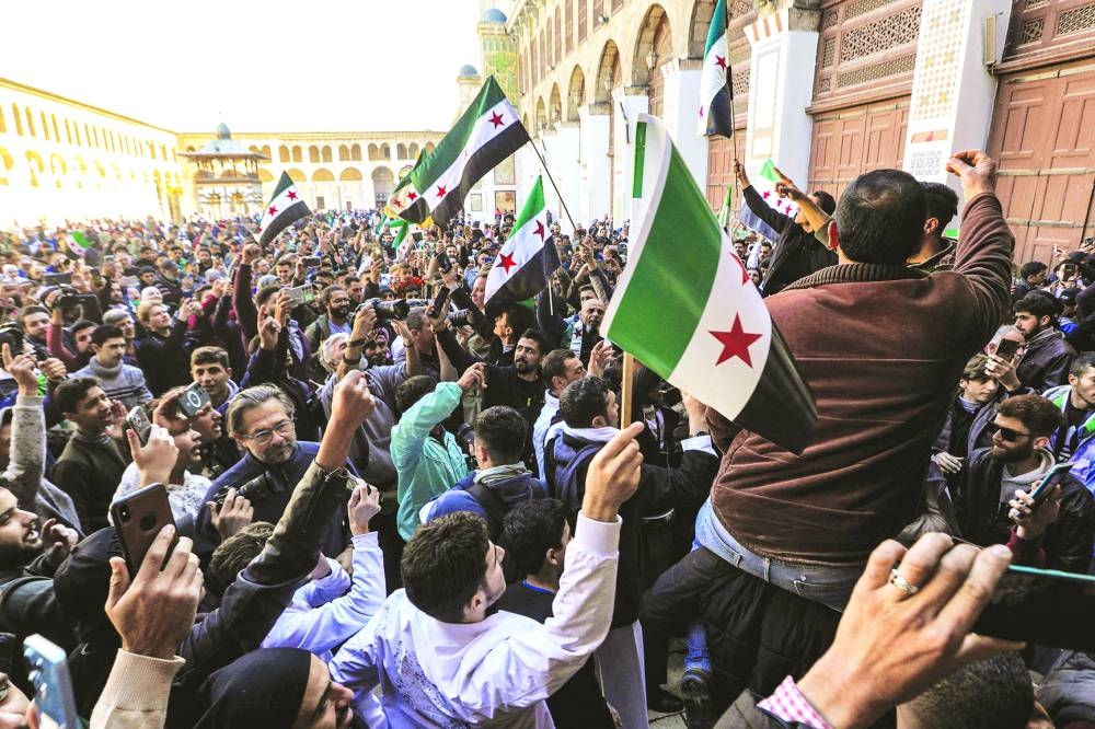 People chant slogans and wave independence-era Syrian flags as they gather in the courtyard of the Umayyad mosque in the old city of Damascus Friday.
