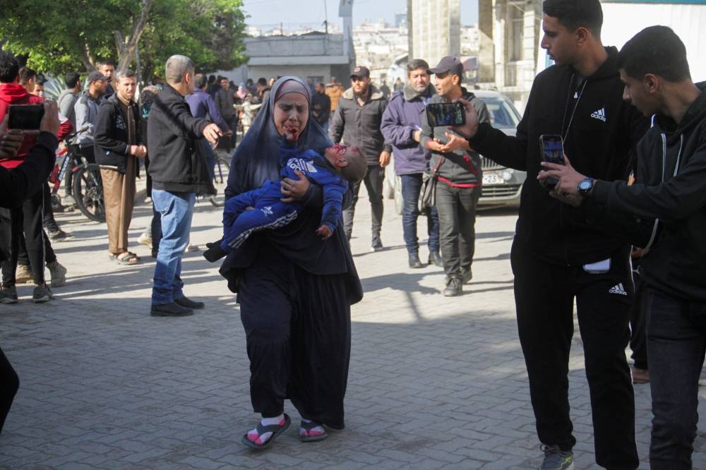 A Palestinian woman carries a child casualty at the site of an Israeli strike on a school sheltering displaced people, in Gaza City, on Saturday. REUTERS