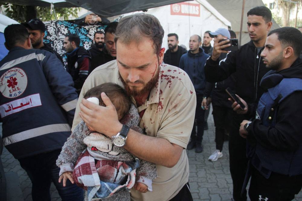 A Palestinian man carries a child casualty at a hospital, in the aftermath of an Israeli strike on a school sheltering displaced people, in Gaza City, on Saturday. REUTERS