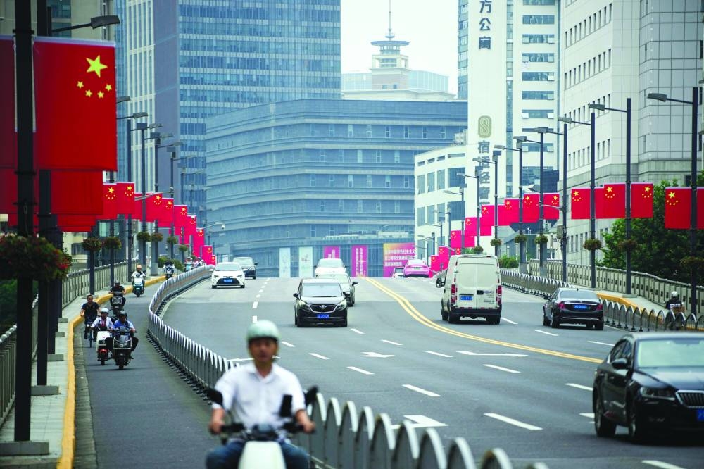Chinese flags are seen on a street in Shanghai. China pledged on Thursday to issue more debt and loosen monetary policy to maintain a stable economic growth rate.