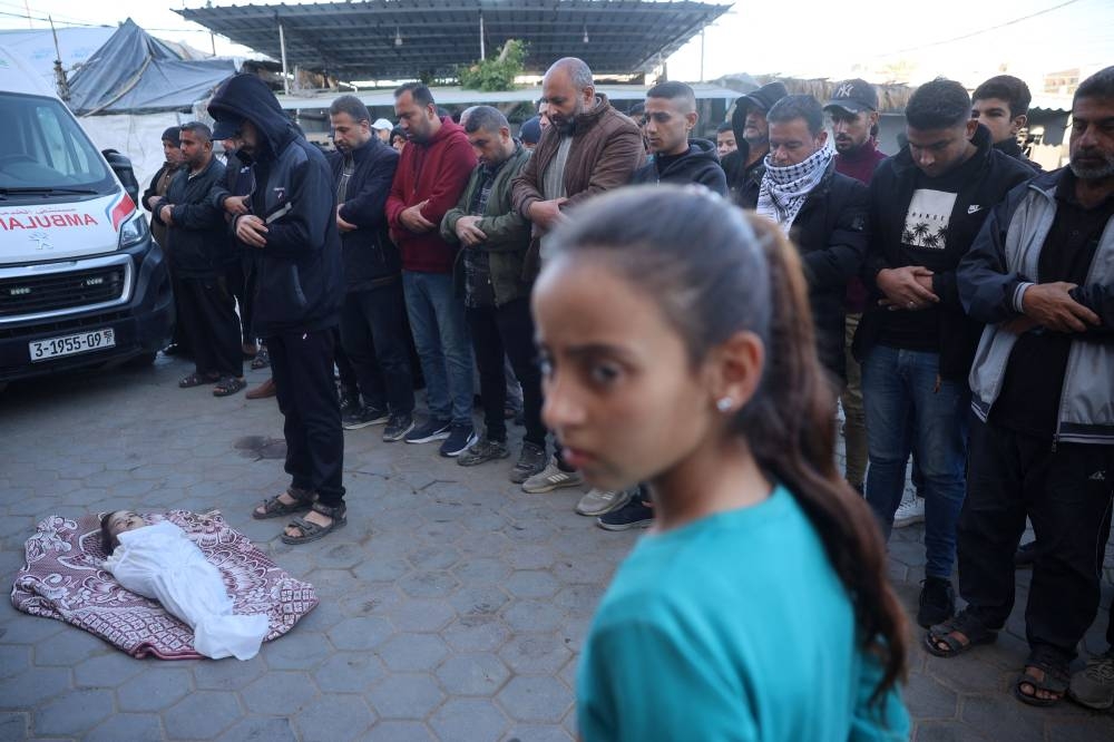 Palestinians pray over the body of a child, killed in an Israeli strike, at the Al-Aqsa Martyrs Hospital in Deir el-Balah in the central Gaza Strip, on Sunday. AFP
