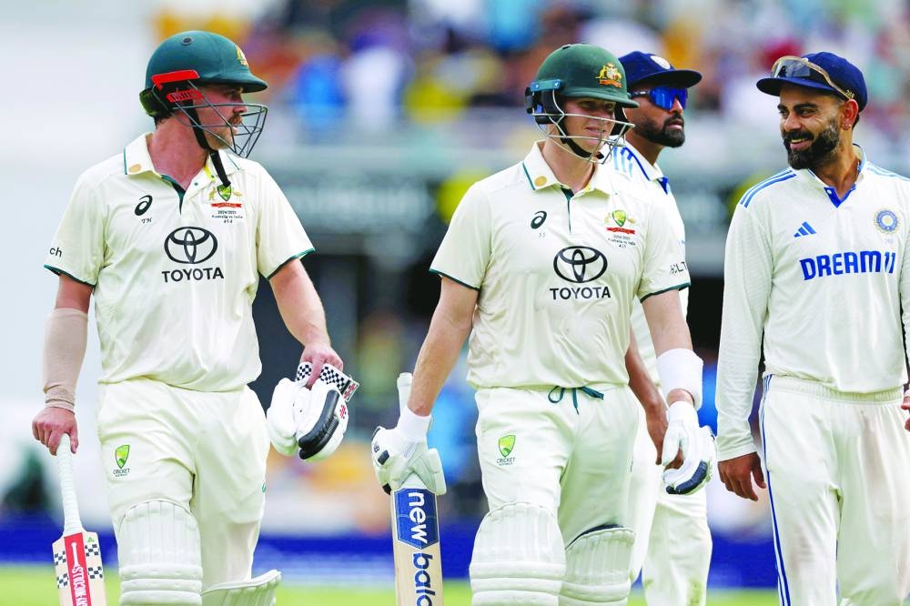 Australia’s Travis Head (left) and Steve Smith (centre) talk with India’s Virat Kohli as they walk off the ground for the tea break on day two of the third Test at The Gabba in Brisbane yesterday. (AFP)