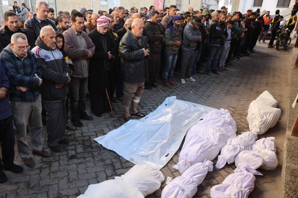 Palestinians pray next to shrouded bodies ahead of a funeral at Al-Ahli Arab hospital, also known as the Baptist hospital, in Gaza City on Tuesday. AFP