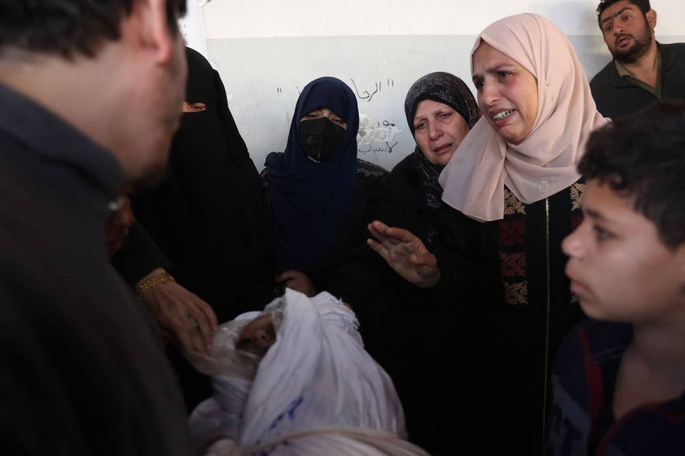 Palestinians mourn as they carry the shrouded body of a child at Al-Ahli Arab hospital, also known as the Baptist hospital, in Gaza City on Tuesday. AFP