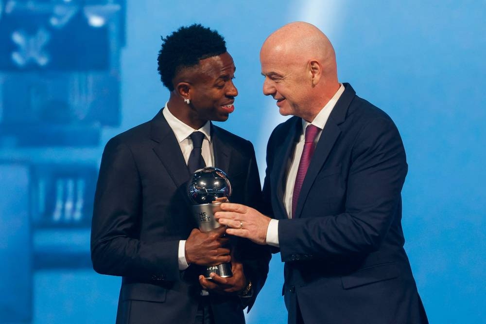 Brazilian forward Vinicius Junior (L) receives the Best Player trophy from FIFA President Gianni Infantino during the Best FIFA Football Awards 2024 ceremony held at Aspire Academy in Doha Tuesday.