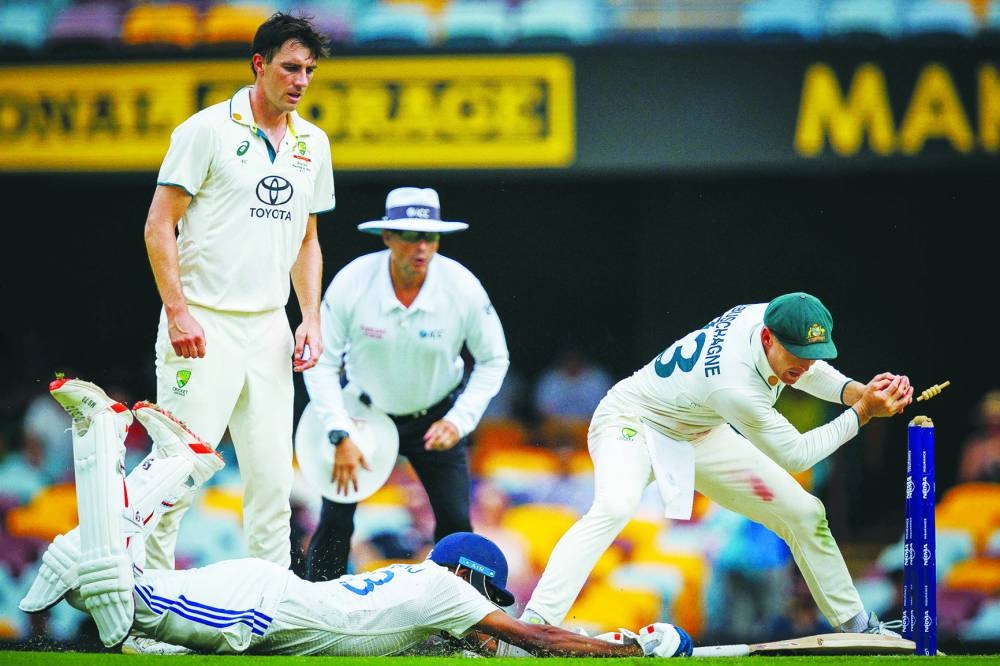 
Australia’s captain Pat Cummins (left) looks on as Marnus Labuschagne (right) attempts the run out of India’s Mohammed Siraj on day four of the third Test at The Gabba in Brisbane yesterday. (AFP) 