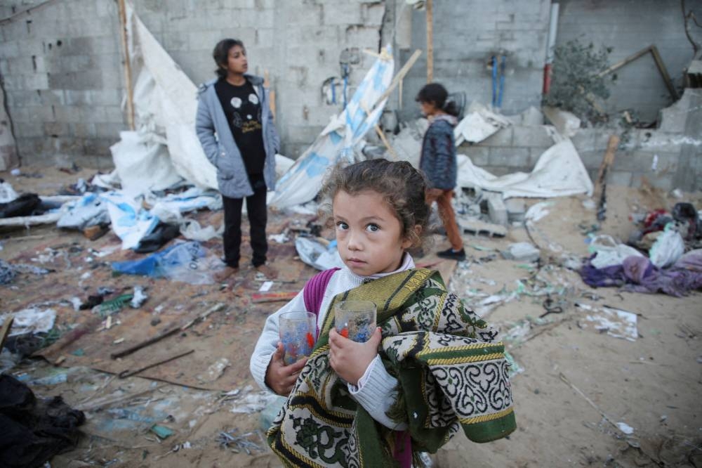 A Palestinian girl holds glasses in her hands as she stands amidst the damage at a tent camp sheltering displaced people, following an Israeli strike in Al-Mawasi area, in Khan Younis, southern Gaza Strip, on Wednesday. REUTERS