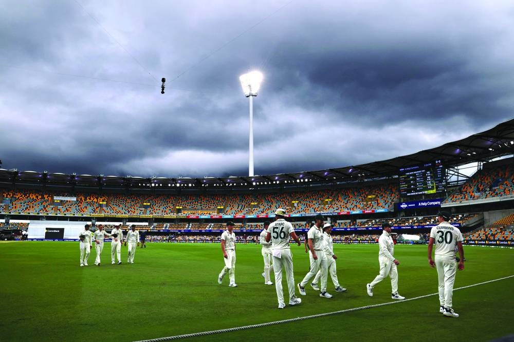 Australia’s captain Pat Cummins (right) leads his team off the ground due to a rain delay on day five of the third Test against India at The Gabba in Brisbane on Wednesday. (AFP)