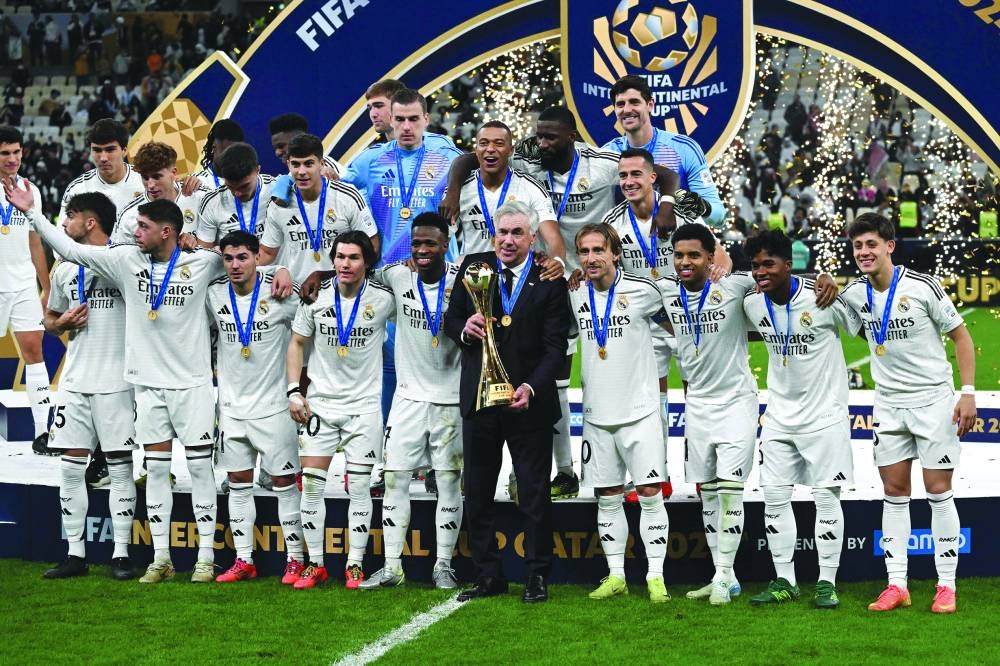Real Madrid's Italian coach Carlo Ancelotti holds the tournament trophy as he poses with his players for the group picture at the podium ceremony after the 2024 FIFA Intercontinental Cup final football match between Spain's Real Madrid and Mexico's Pachuca at the Lusail Stadium in Doha Wednesday.