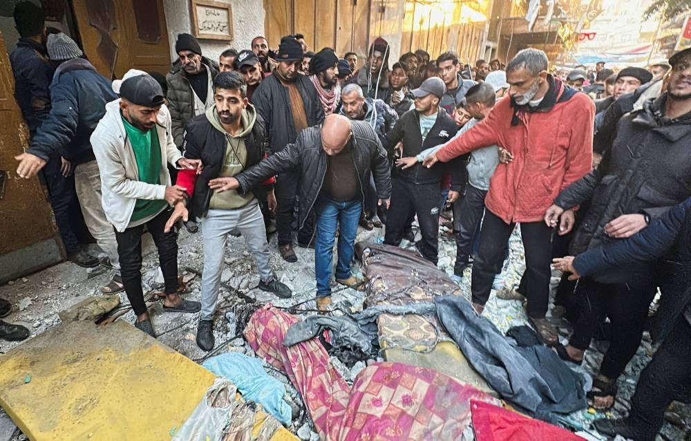 Palestinians inspect damage at the site of an Israeli strike on an apartment, in Nuseirat, central Gaza Strip, on Friday. REUTERS