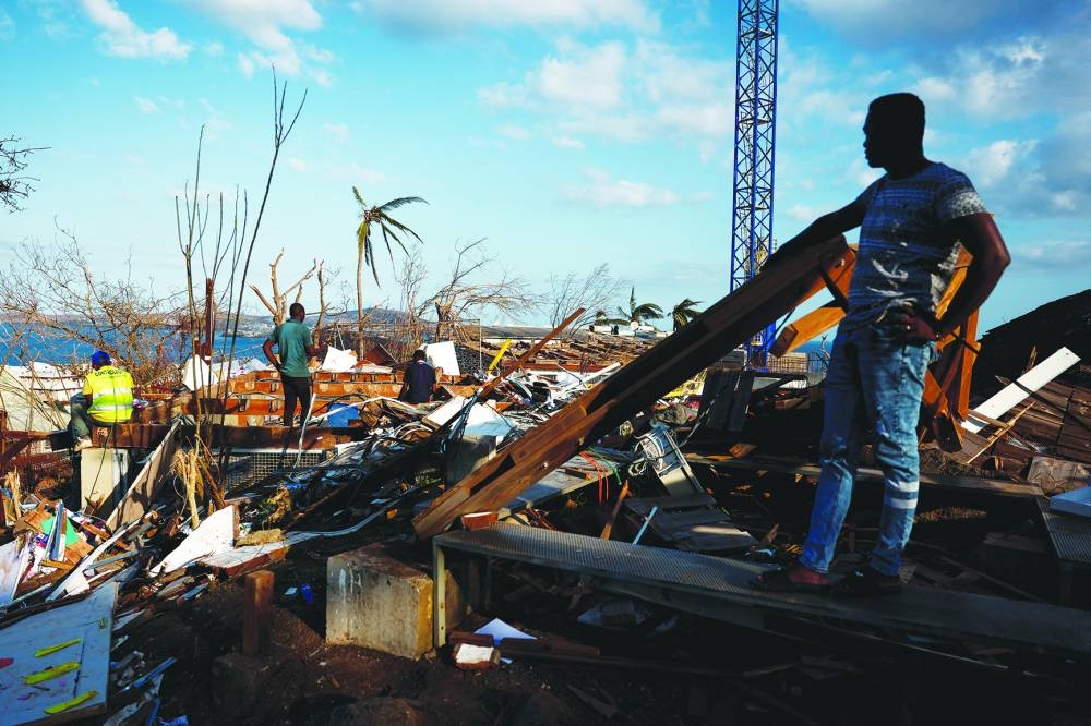 People clean the debris around the destroyed houses in the aftermath of Cyclone Chido, in Mamoudzou, Mayotte, France December 20, 2024. REUTERS/Gonzalo Fuentes