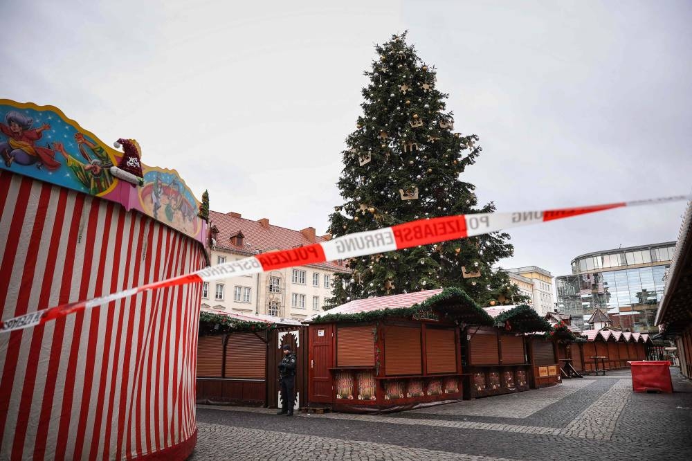 Police guards behind a cordon the closed Christmas market where a car crashed into a crowd injuring more than 60 people the evening before, on early Saturday in Magdeburg, eastern Germany. AFP