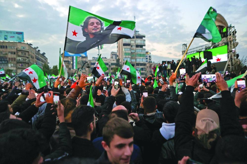 
People wave an independence-era flag bearing the image of late rebel fighter and famous chanter Abdel-Basset al-Sarout at Aleppo’s Saadallah al-Jabri Square as they take part in the “Liberation Festival”, celebrating the fall of president Bashar al-Assad, yesterday. 
