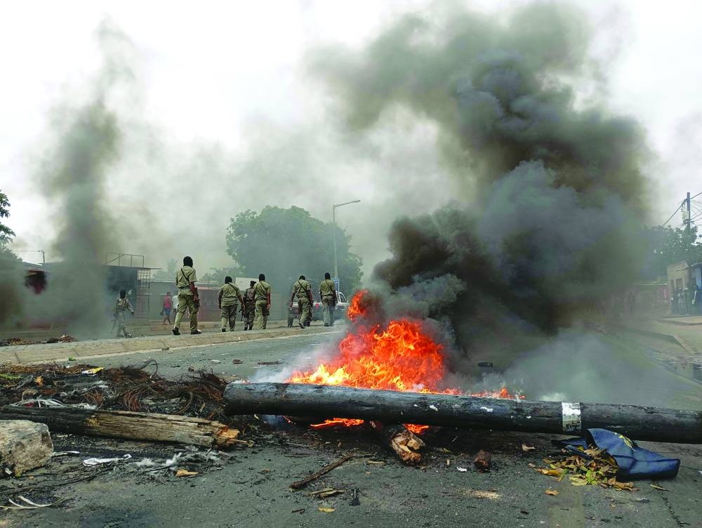 
Pedestrians walk past a burning barricade in Maputo yesterday. 