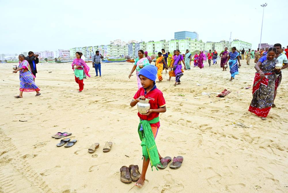 People carry milk pots to pour into the Bay of Bengal as a gesture of respect to the victims of the 2004 Indian Ocean tsunami on the 20th anniversary of the disaster, at Pattinapakkam beach in Chennai, India, on Thursday.
