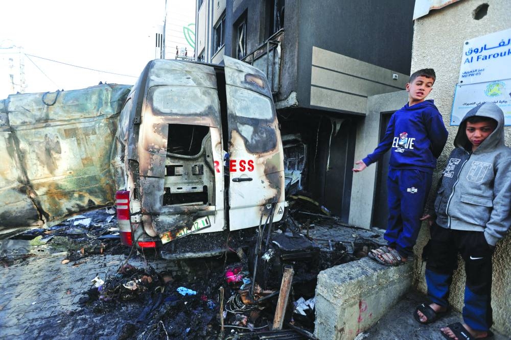 Palestinians stand near the remains of a broadcasting vehicle following an Israeli airstrike that killed five journalists near Al-Awda Hospital,  Nuseirat, central Gaza Strip,on Thursday 