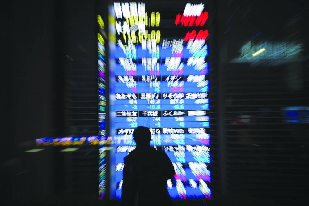 
A pedestrian looks at an electronics stock indicator displaying the Tokyo Stock Exchange in Tokyo. Japan’s Nikkei jumped 0.38% and was on track to end the year with a more than 17% gain. 
