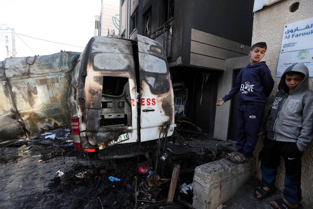 Palestinians stand near the remains of a broadcasting vehicle following an Israeli airstrike that killed five journalists from Al-Quds Al-Youm television channel near Al-Awda Hospital in Nuseirat, central Gaza Strip, on Thursday. REUTERS