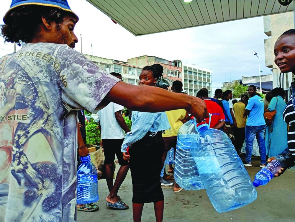 
Motorists carry plastic containers as they queue at a petrol station. 