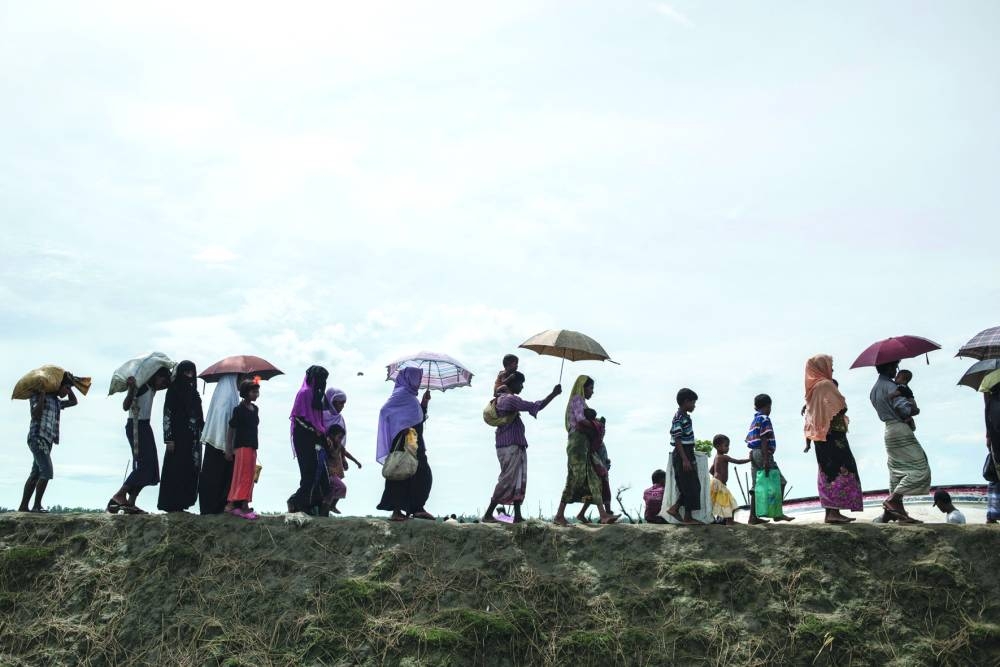 
Rohingya refugees walk toward refugee camps after crossing the border from Myanmar at the Bangladeshi shores of the Naf river in Teknaf in a file picture. 