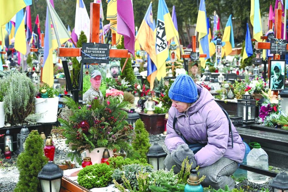 
A woman mourns next to the grave of a fallen Ukrainian soldier at the Lychakiv Military Cemetery in Lviv yesterday. (AFP) 