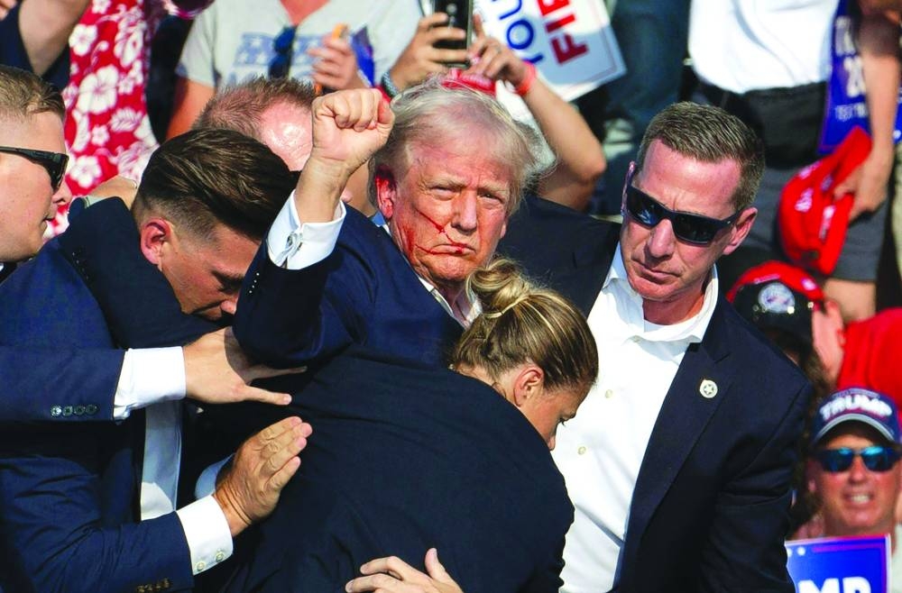 
Republican Presidential candidate Donald Trump is seen with blood on his face surrounded by secret service agents as he is taken off the stage at a campaign event at Butler Farm Show Inc, in Butler, Pennsylvania, on July 13. Trump was hit in the ear in an apparent assassination attempt by a gunman at the campaign rally in a chaotic and shocking incident. (AFP) 