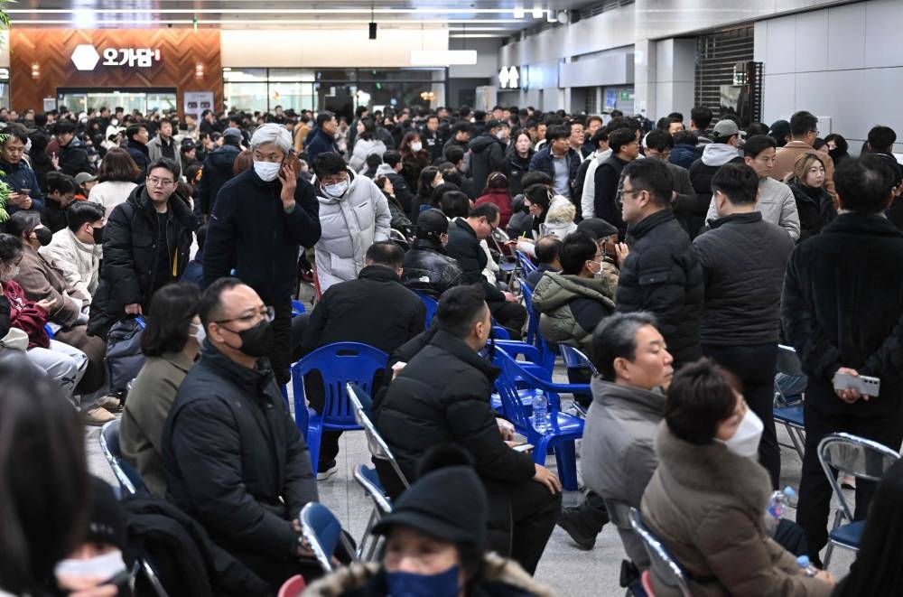 People and relatives of passengers of the crashed Jeju Air Boeing 737-800 series aircraft react at Muan International Airport. AFP