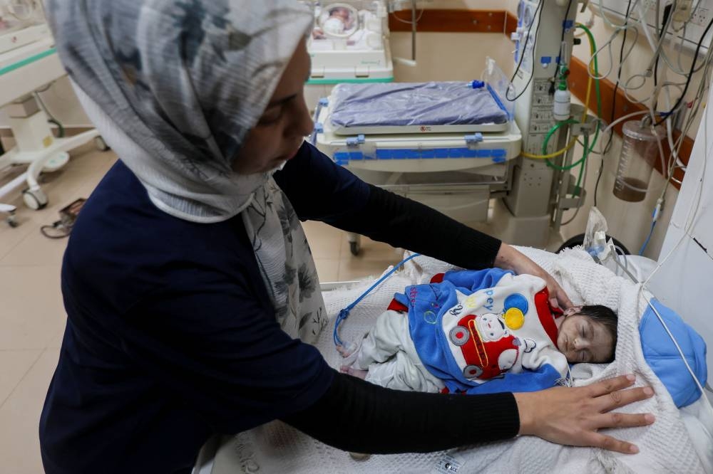 A nurse checks the body of Palestinian infant Jumaa Al-Batran, who died of hypothermia after living in a tent with his displaced family, according to doctors, at Al-Aqsa Martyrs Hospital in Deir Al-Balah, central Gaza Strip, on Sunday. REUTERS