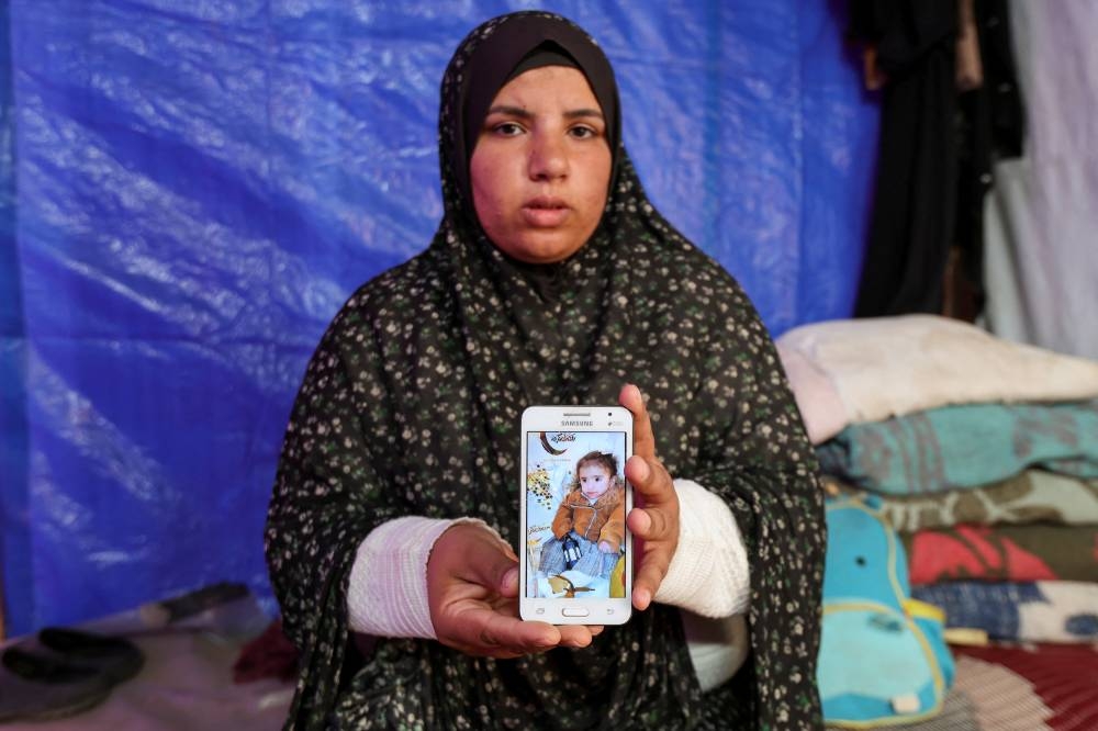 Sahar, the mother of Palestinian girl Elena al-Sheikh Khalil, who doctors said died due to malnutrition, displays a picture of her daughter on a mobile phone inside a tent where she shelters after being displaced from her home, in Deir Al-Balah in the central Gaza Strip on December 5. REUTERS
