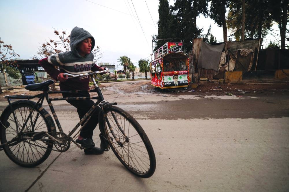 A boy moves his bicycle across the street n Douma, Syria Monday.
