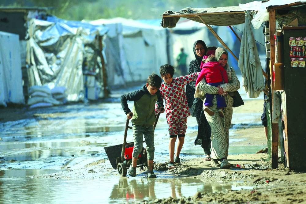 People walk in a flooded area following heavy rain at  a camp in Deir el-Balah in the central Gaza Strip Monday
