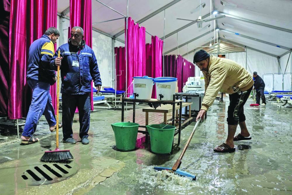 Men mop away the rainwater that flooded the medical tent annex at Nasser Medical Complex in Khan Yunis in the southern Gaza Strip due to a rainstorm Tuesday.