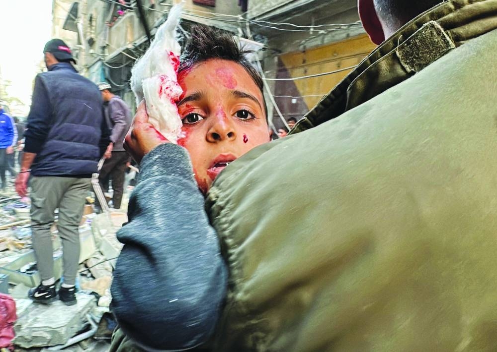 A Palestinian carries a wounded child at the site of an Israeli strike on an apartment in Nuseirat, central Gaza Strip.
