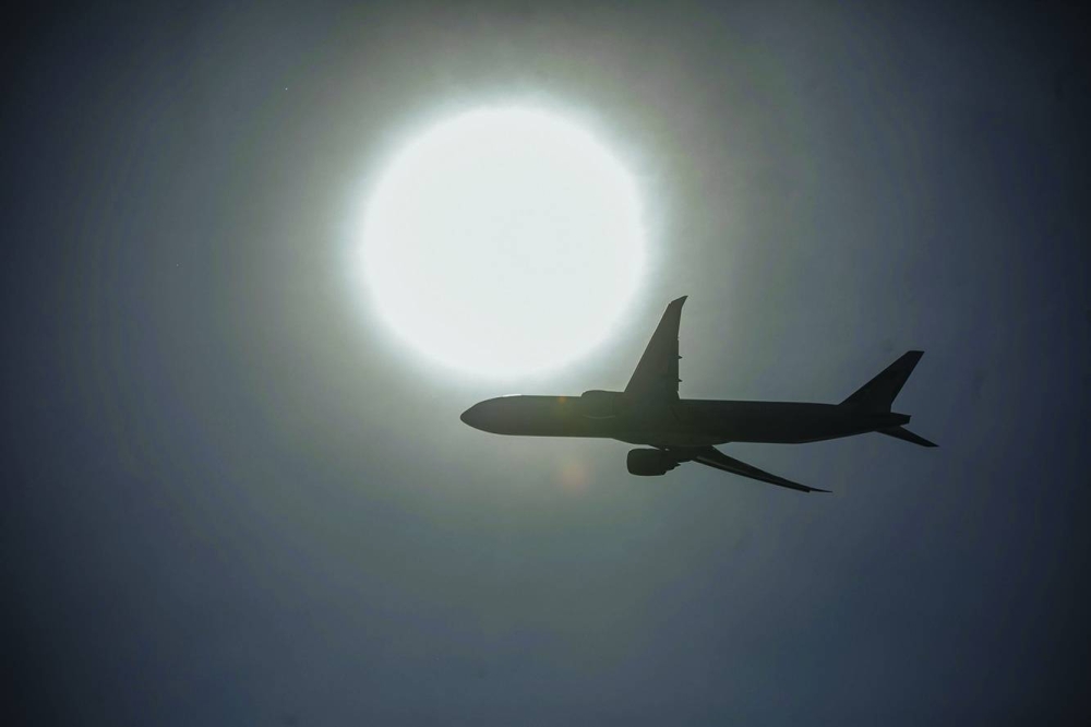 An aircraft is silhouetted as it flies over the Hong Kong International Airport. International flights into Shanghai, Beijing and Hong Kong are set to jump in 2025, almost completing the cities’ recoveries to pre-pandemic totals.