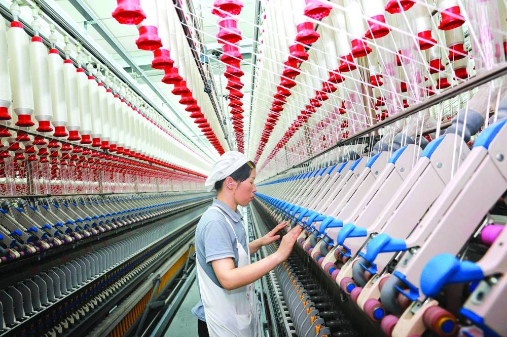 A worker operates machines at a textile factory in Nantong, in eastern China's Jiangsu province. The Caixin/S&P Global manufacturing PMI for China nudged down to 50.5 in December from 51.5 the previous month, undershooting analysts' forecasts and indicating activity grew only modestly.