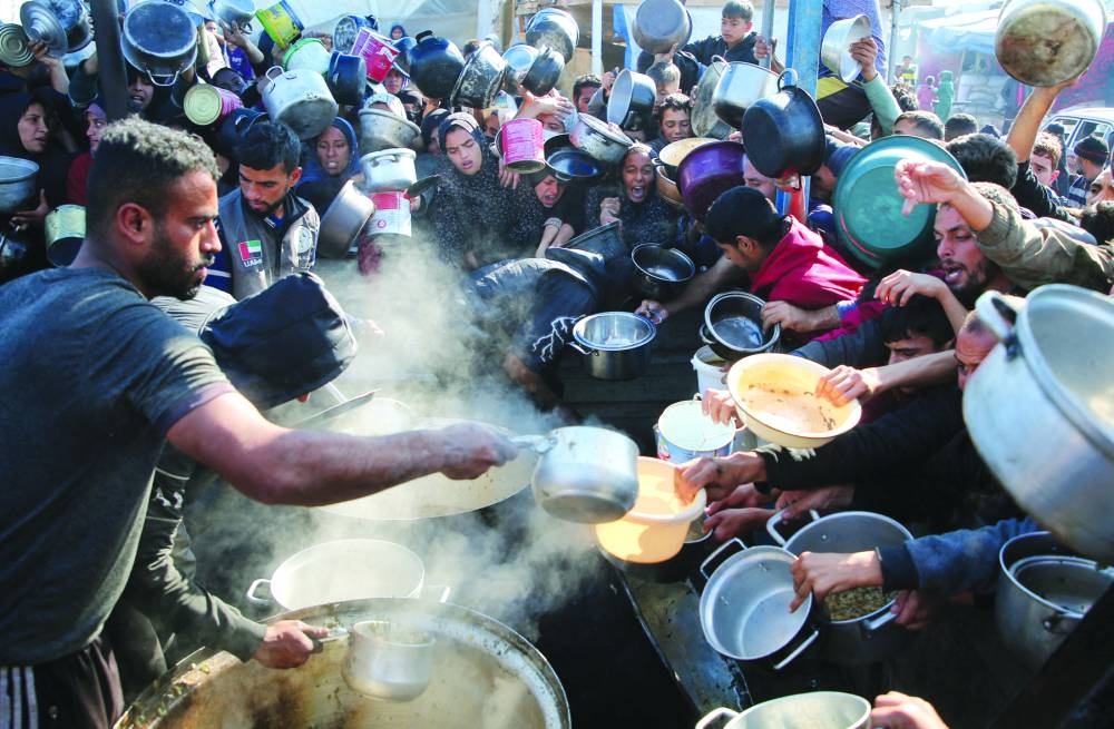 Palestinians gather to receive food cooked by a charity kitchen, in Khan Younis in the southern Gaza Strip,  on Thursday 