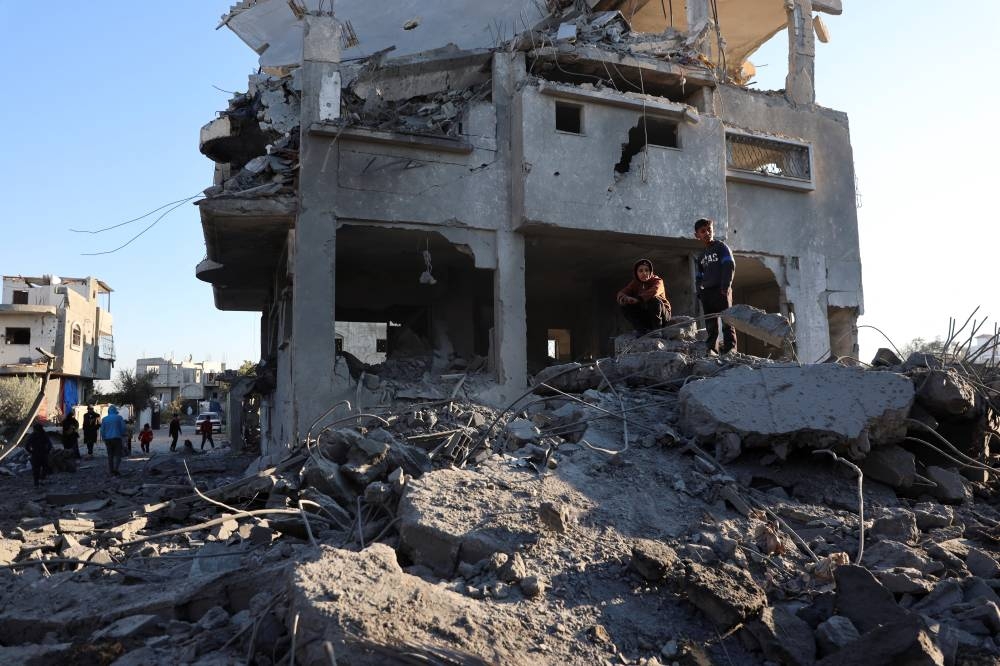 Palestinian boys stand near the site of an Israeli strike on a house in Al Maghazi refugee camp in the central Gaza Strip, on Friday. REUTERS