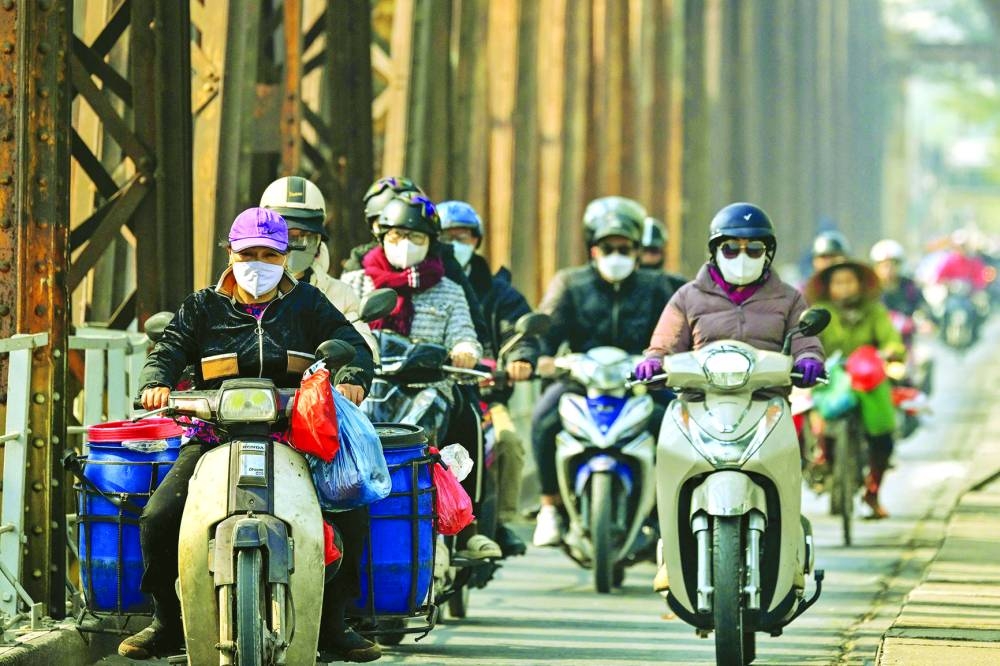 
Motorists wearing face masks ride scooters along Long Bien Bridge amid heavy air pollution in Hanoi. 