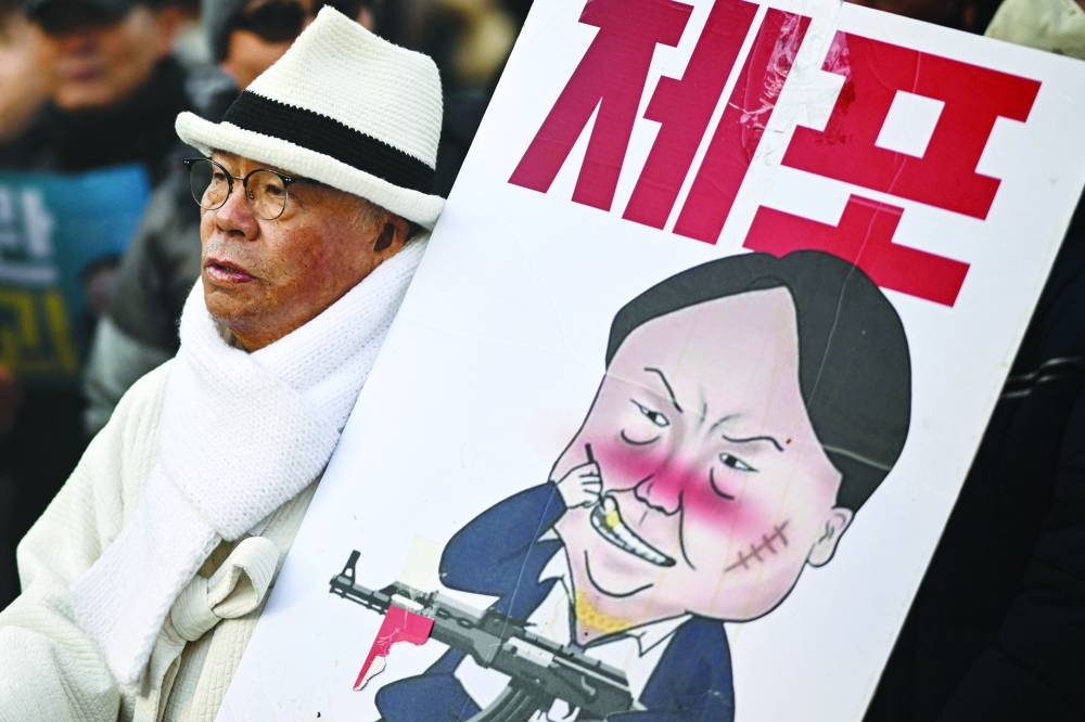 A man carrying a placard with a comic depicting South Korea’s impeached president Yoon Suk-yeol marches during an anti-Yoon rally in Seoul on Friday.