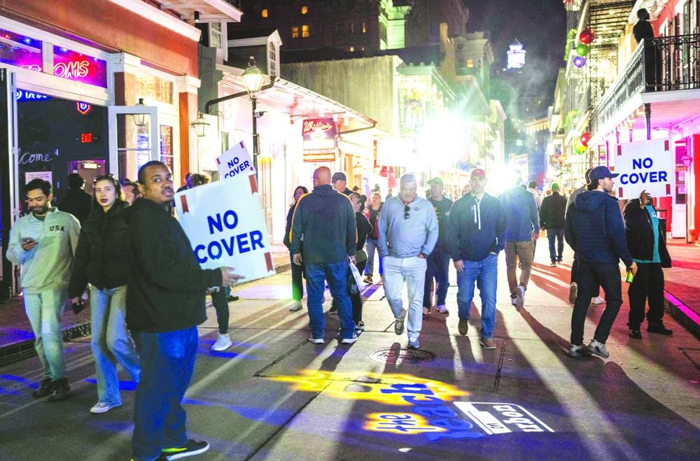 People walk past shops on Bourbon Street in New Orleans after it reopened to the public. – AFP
