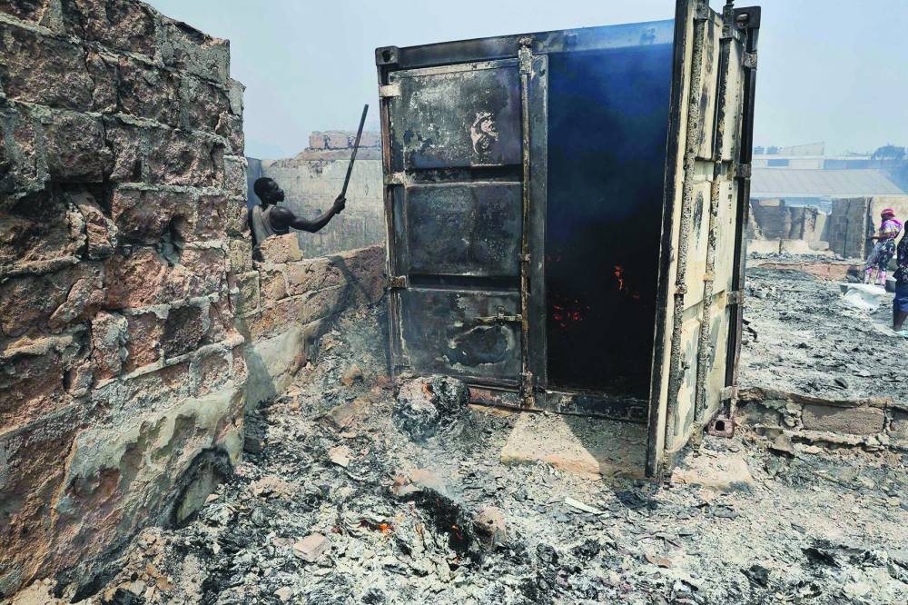 
A man tries to deal with the fire at the burned down secondhand clothing market at Kantamanto. 