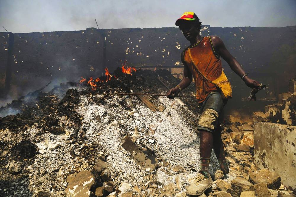 Scrap dealers try to salvage items from the burned down secondhand clothing market at Kantamanto in Accra, Ghana, on January 2, 2025. The fire at the Kantamanto market began in the early morning hours, destroying a large part of the area and displacing thousands of traders. (Photo by Nipah Dennis / AFP)