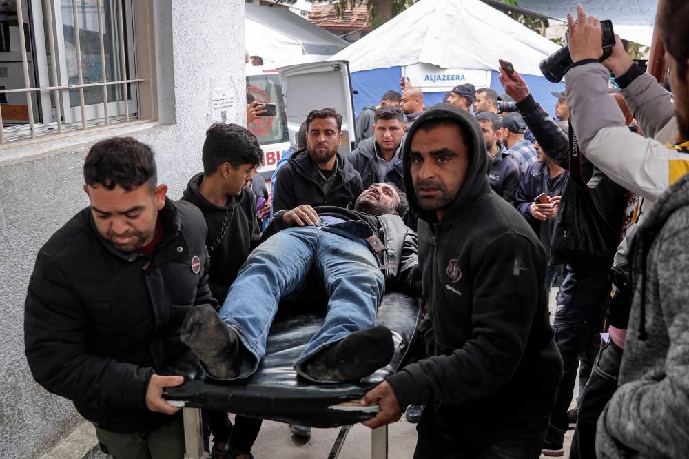 An injured man is carried on a gurney for care at the Ahli Arab hospital, also known as the Baptist hospital, in Gaza City on Saturday. AFP