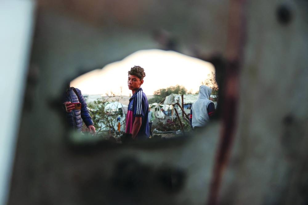 
A displaced Palestinian boy stands amid damaged tents following an Israeli strike on a makeshift displacement camp in Mawasi, Khan Yunis, in the southern Gaza Strip. (AFP) 