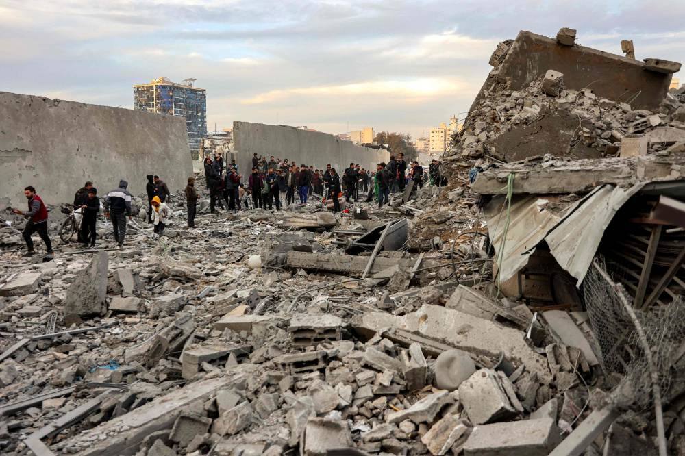 People and first responders inspect the rubble of a collapsed residential building that was hit by Israeli bombardment in the Saraya area in al-Rimal in central Gaza City on Saturday. AFP