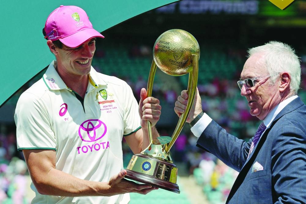 
Australia’s captain Pat Cummins (left) is handed the trophy by former Australian skipper Allan Border after winning the match and series on day three of the fifth Test against India at the SCG yesterday. (AFP) 