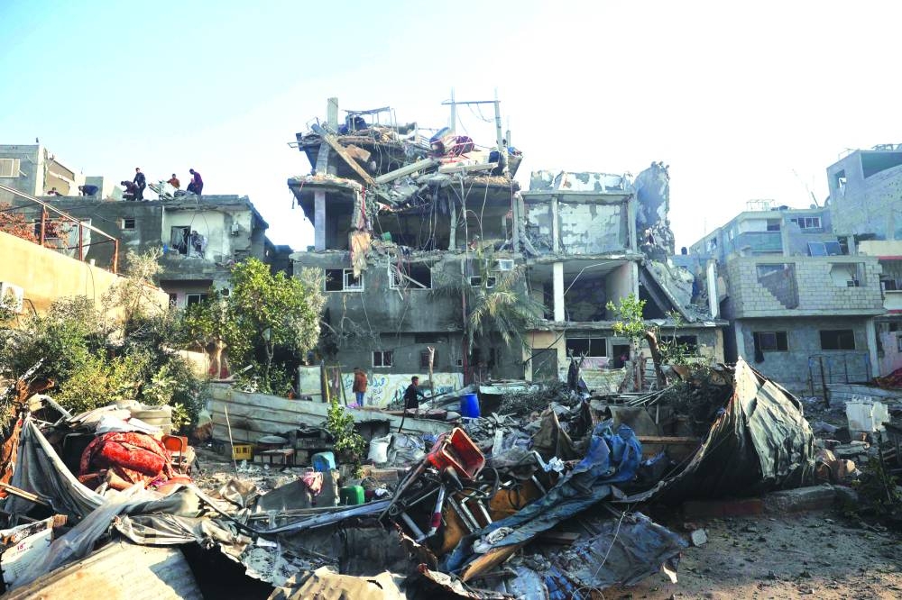 People look for their belongings amid the debris of destroyed buildings following an Israeli air strike on Bureij camp Monday