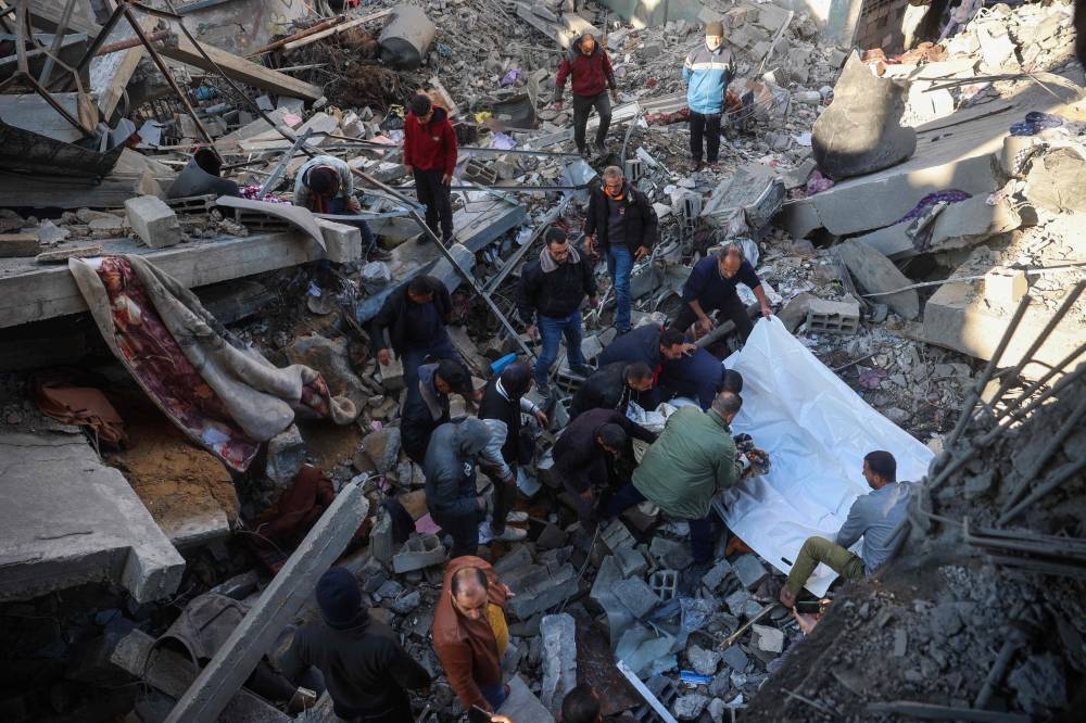People pull out bodies of casualties from the rubble of a building destroyed in an Israeli strike on the Bureij camp for Palestinian refugees in the central Gaza Strip, on Wednesday. AFP 